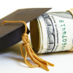 A roll of hundred dollar bills next to a graduation cap with a tassel.