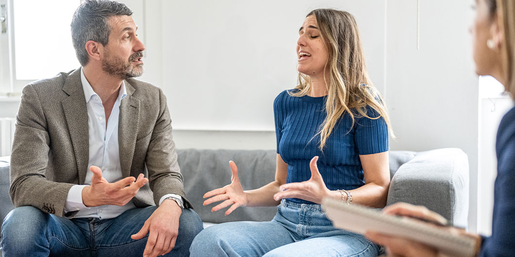 man and woman arguing while sitting on a couch