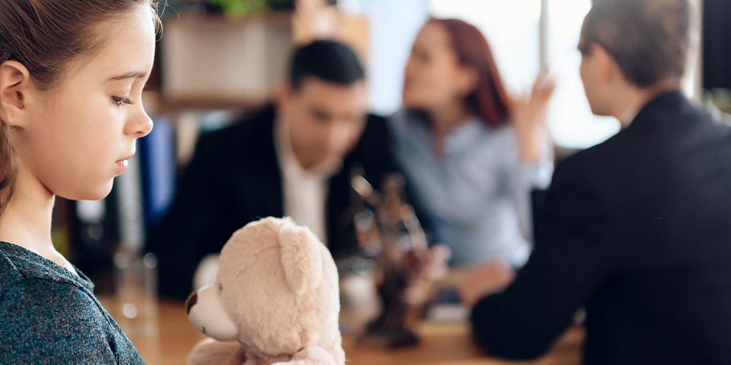 young girl holding teddy bear near adults